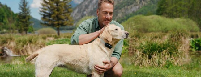 A man with a dog that's wearing a Tractive GPS tracker
